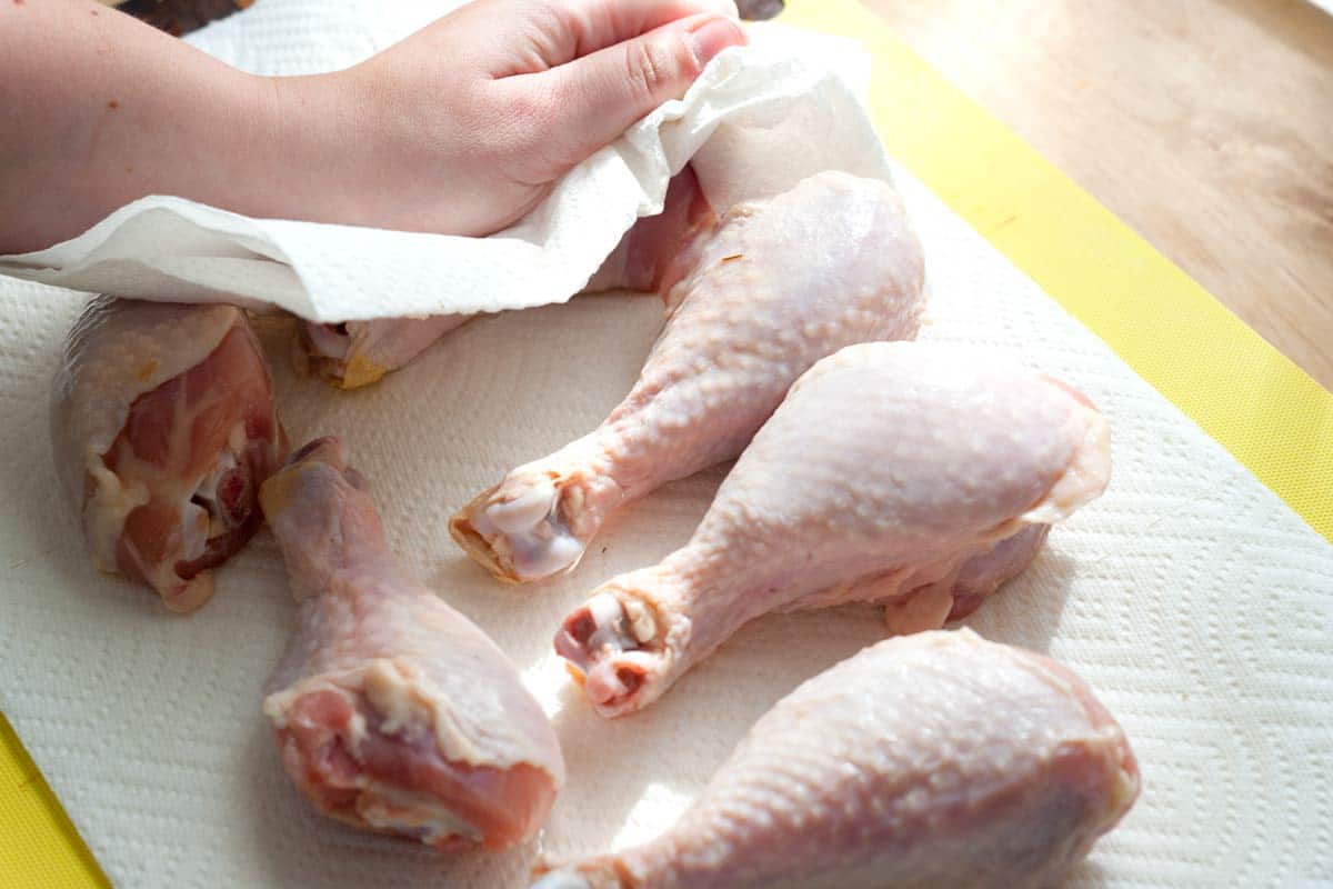 Patting chicken drumsticks dry before baking