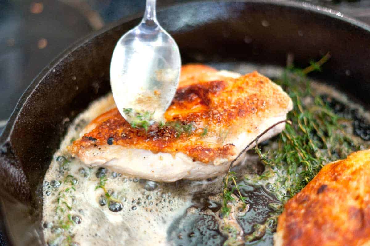 Spooning the thyme butter over the chicken