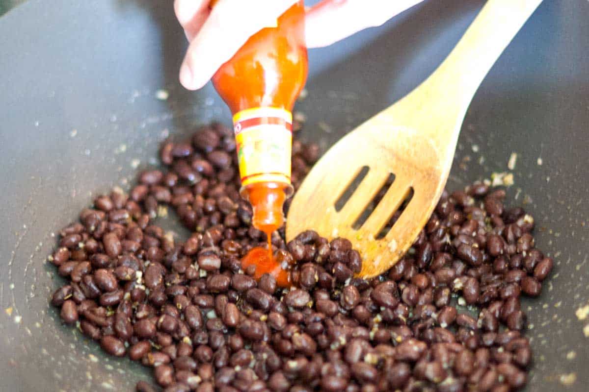 Easy Black Bean Pizza Topped with Salad Adding hot sauce