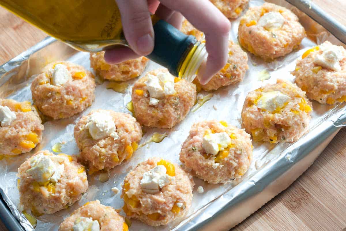 Drizzling the meatballs with olive oil before baking