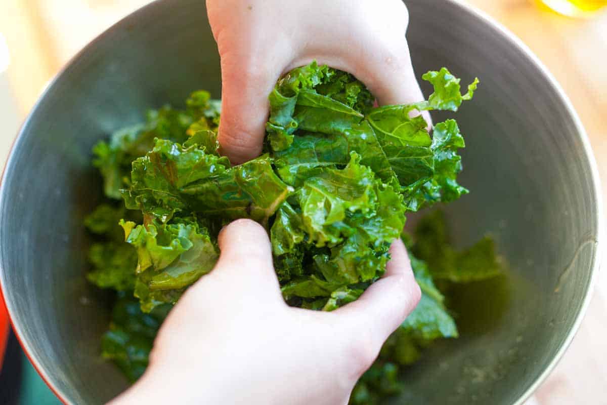 How to Make Kale Chips: Tossing kale with salt, pepper, and olive oil.