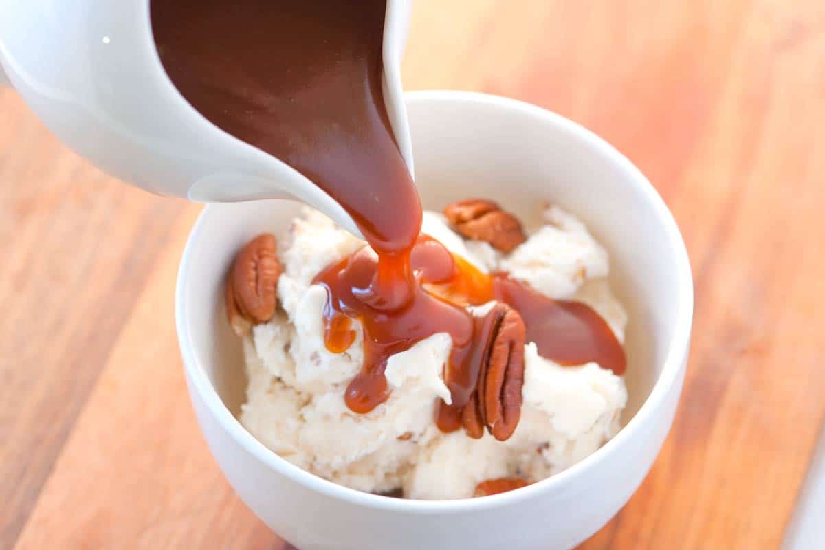 Irresistible Salted Caramel Sauce Recipe Homemade Caramel Sauce being poured over ice cream.