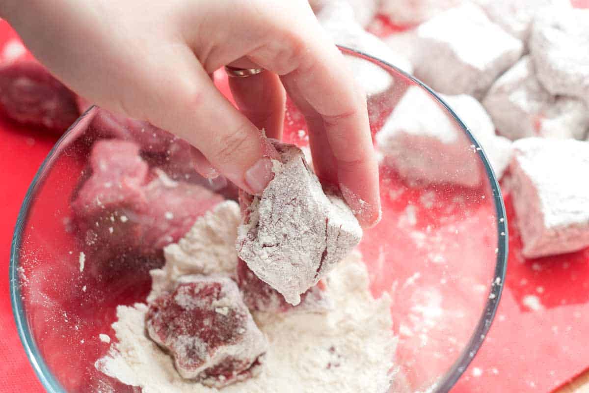 Rolling beef stew meat in seasoned flour