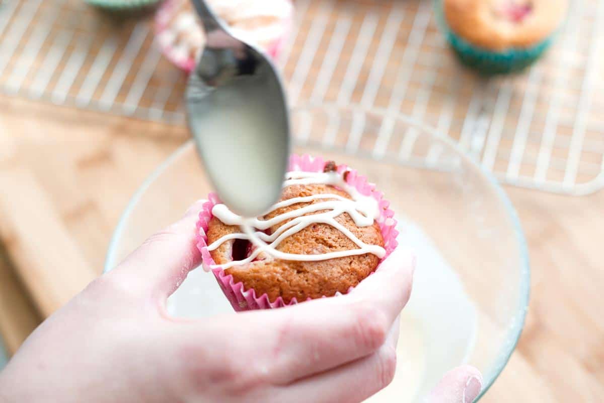 Adding the vanilla glaze to strawberry muffins