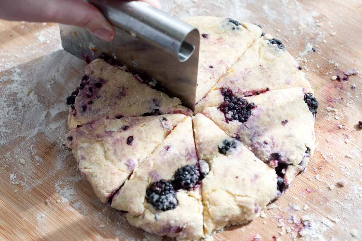 Cutting blackberry scone dough into scones shaped like triangles