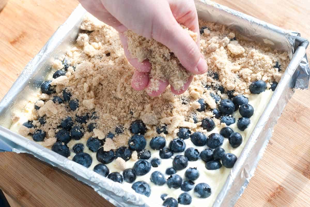 Blueberry Lemon Cheesecake Bars Recipe How to Make Cheesecake Bars: Adding the blueberries and streusel topping