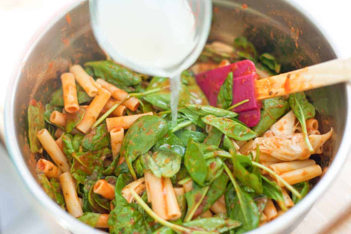 How to Make Spinach Artichoke Baked Ziti: Tossing slightly undercooked pasta with marinara sauce, spinach, artichokes, and a little starchy pasta water.