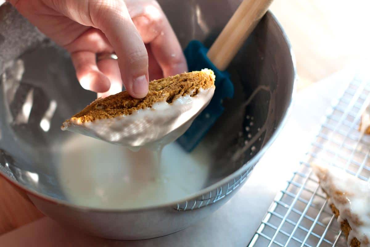 Dipping baked pumpkin scones into vanilla glaze.