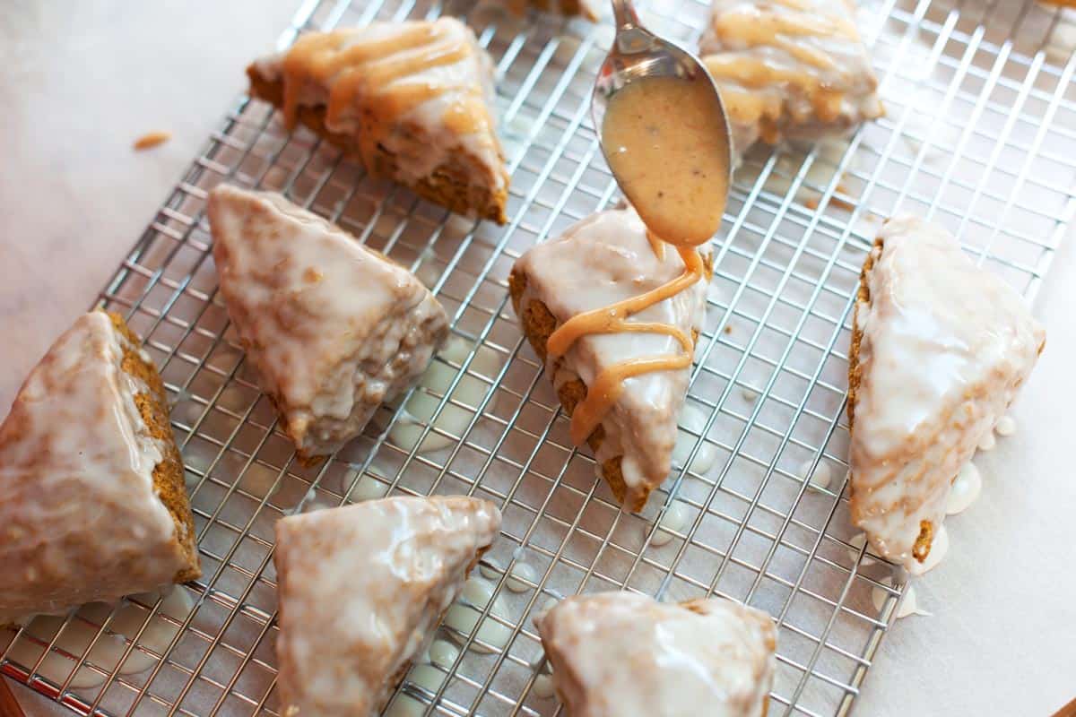 Drizzling homemade Pumpkin Scones with a pumpkin spice glaze