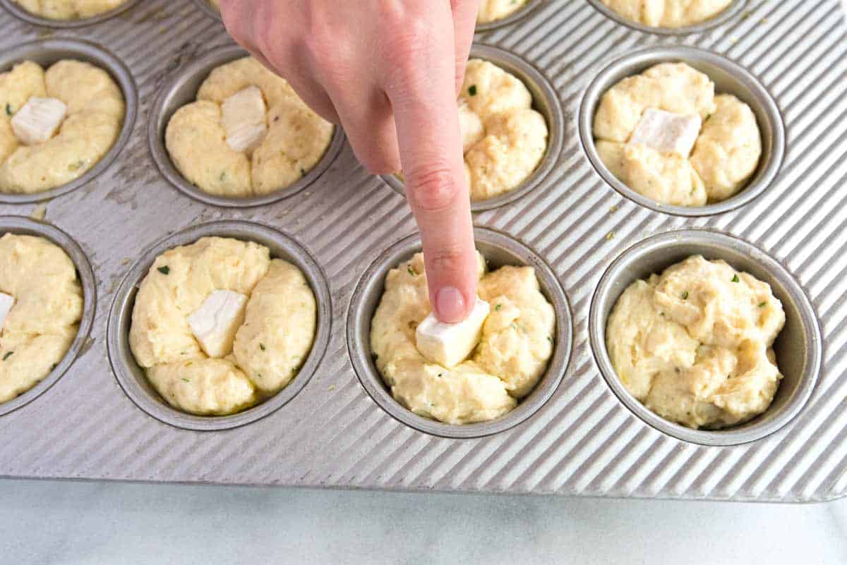 Adding the brie cheese to the middle of each unbaked roll.