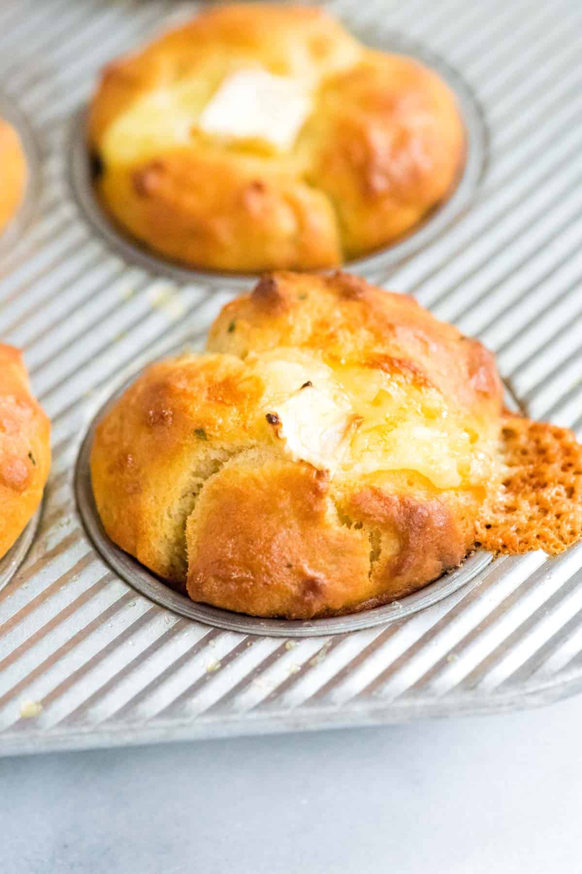 Homemade rolls still in a baking pan with cheese stuffed into the middle.