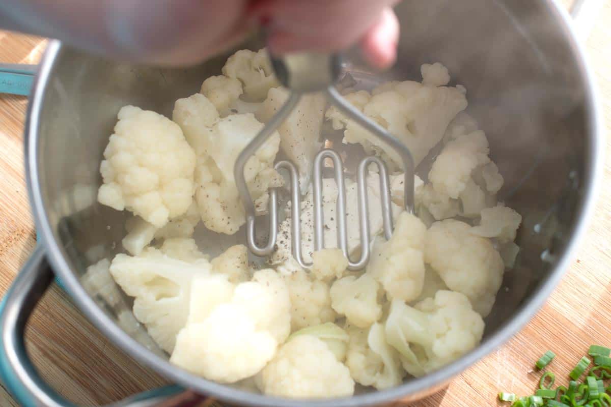 Mashing cauliflower with potato masher