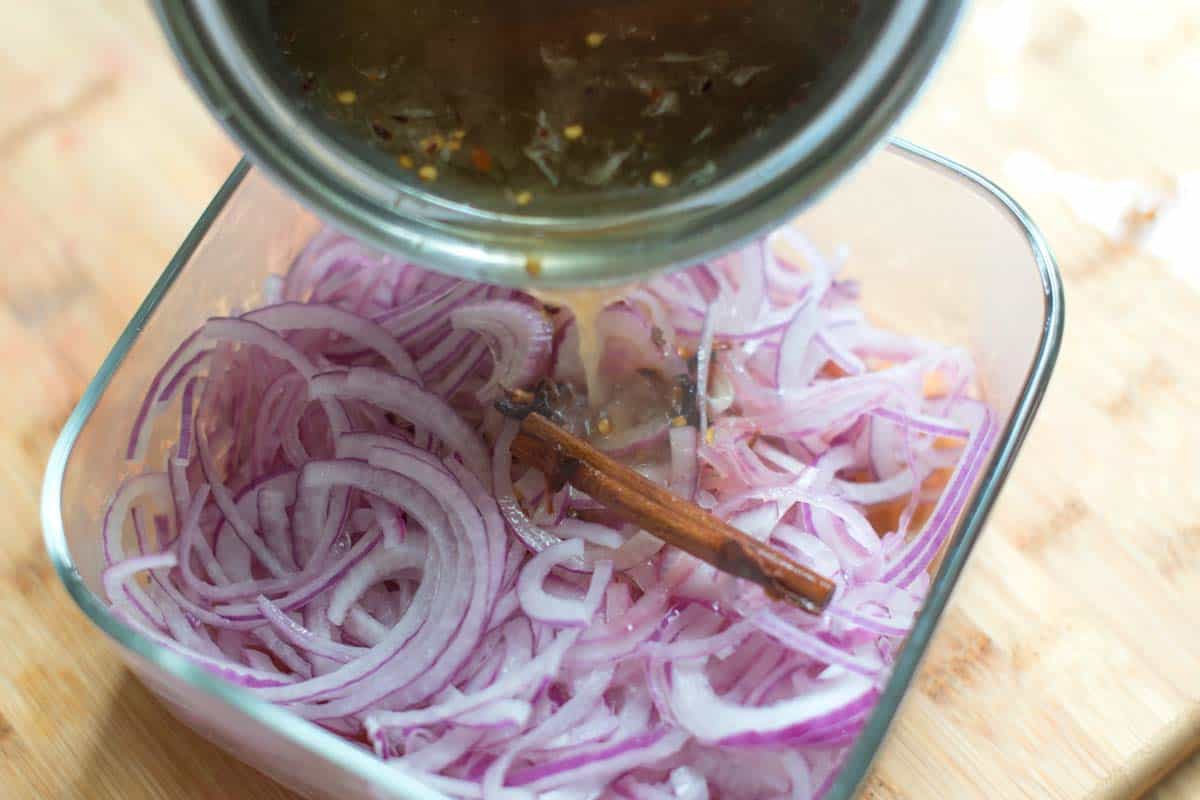 How to Make Pickled Red Onions - Pouring the brine over sliced red onions.