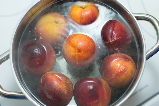 Peeling peaches for cobbler: Simmering the peaches in water to help the peel release.