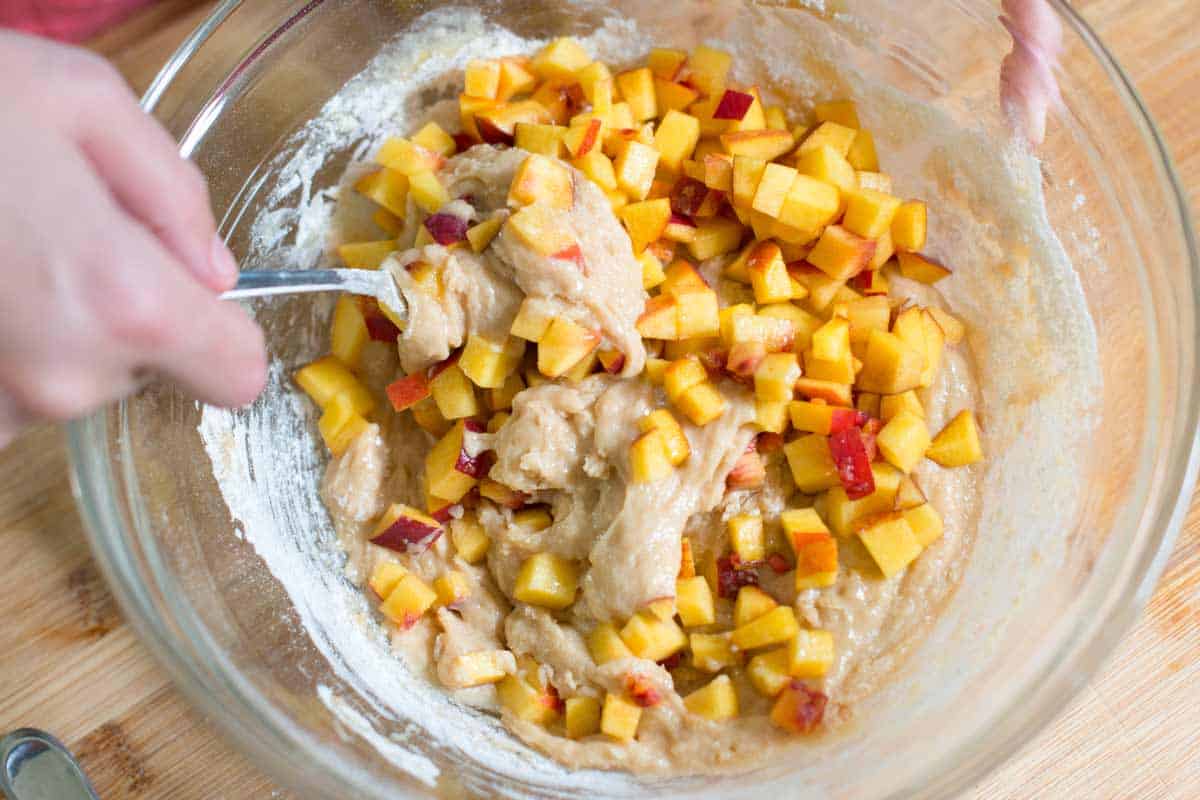 Stirring in the fresh peaches to the muffin batter