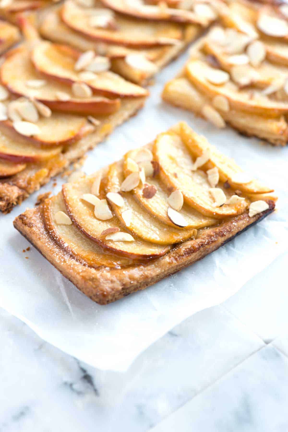 Apple tart with sliced apples, flaky pie crust and almonds on top