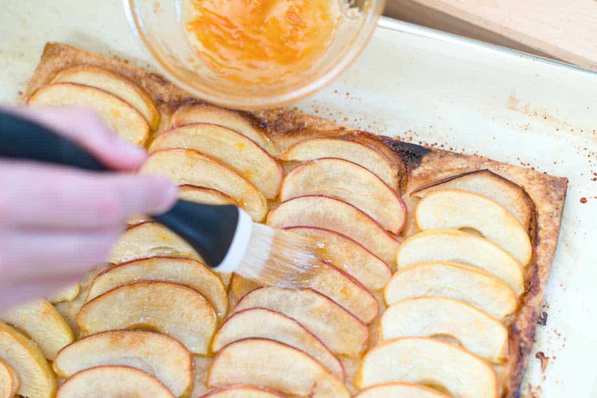 Making the apple tart -- Add jam to the apples.