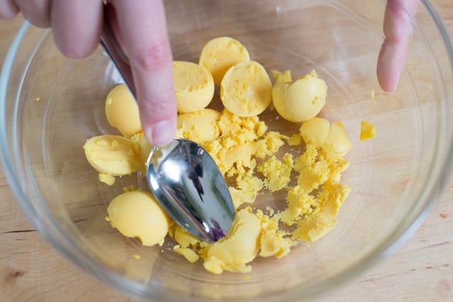 Making deviled eggs filling by smooshing egg yolks.