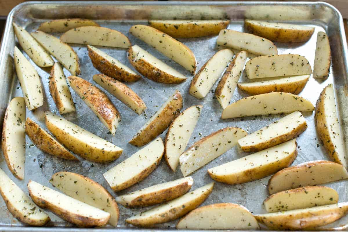 How to Make the Best Roasted Potato Wedges: Seasoned potato wedges on a baking sheet ready to bake.