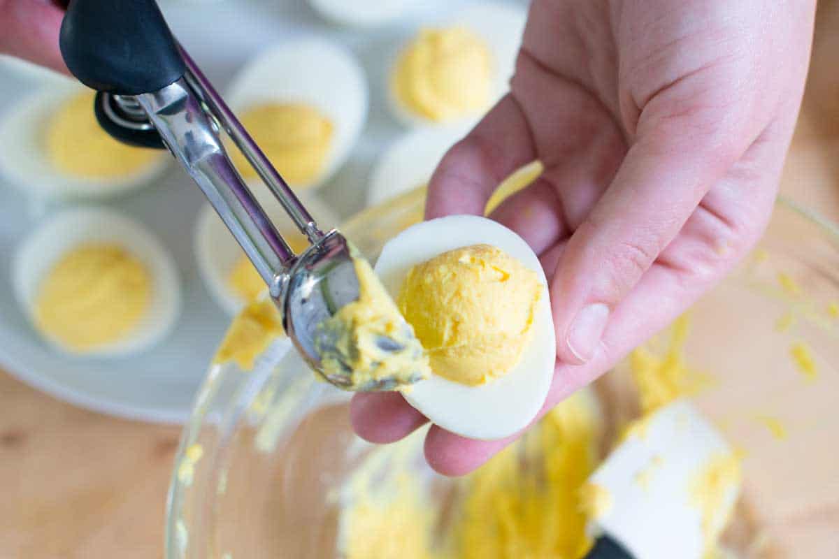 using my small cookie scoop to add the deviled egg filling to the egg white halves