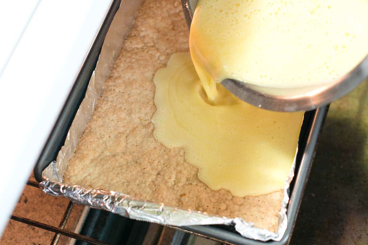 How to Make Lemon Bars: Pouring the lemon filling onto the shortbread crust