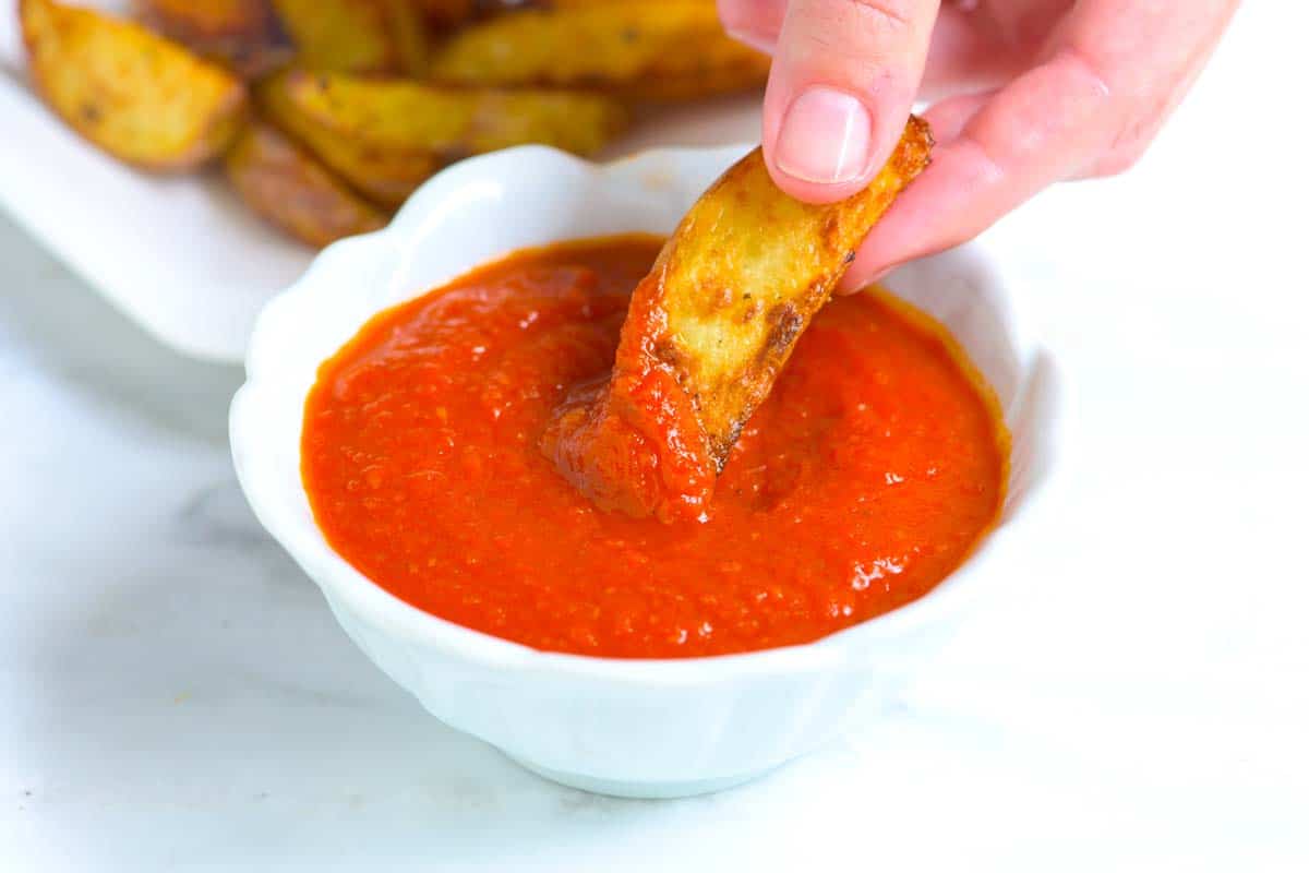 Dipping potato wedges into the best homemade ketchup