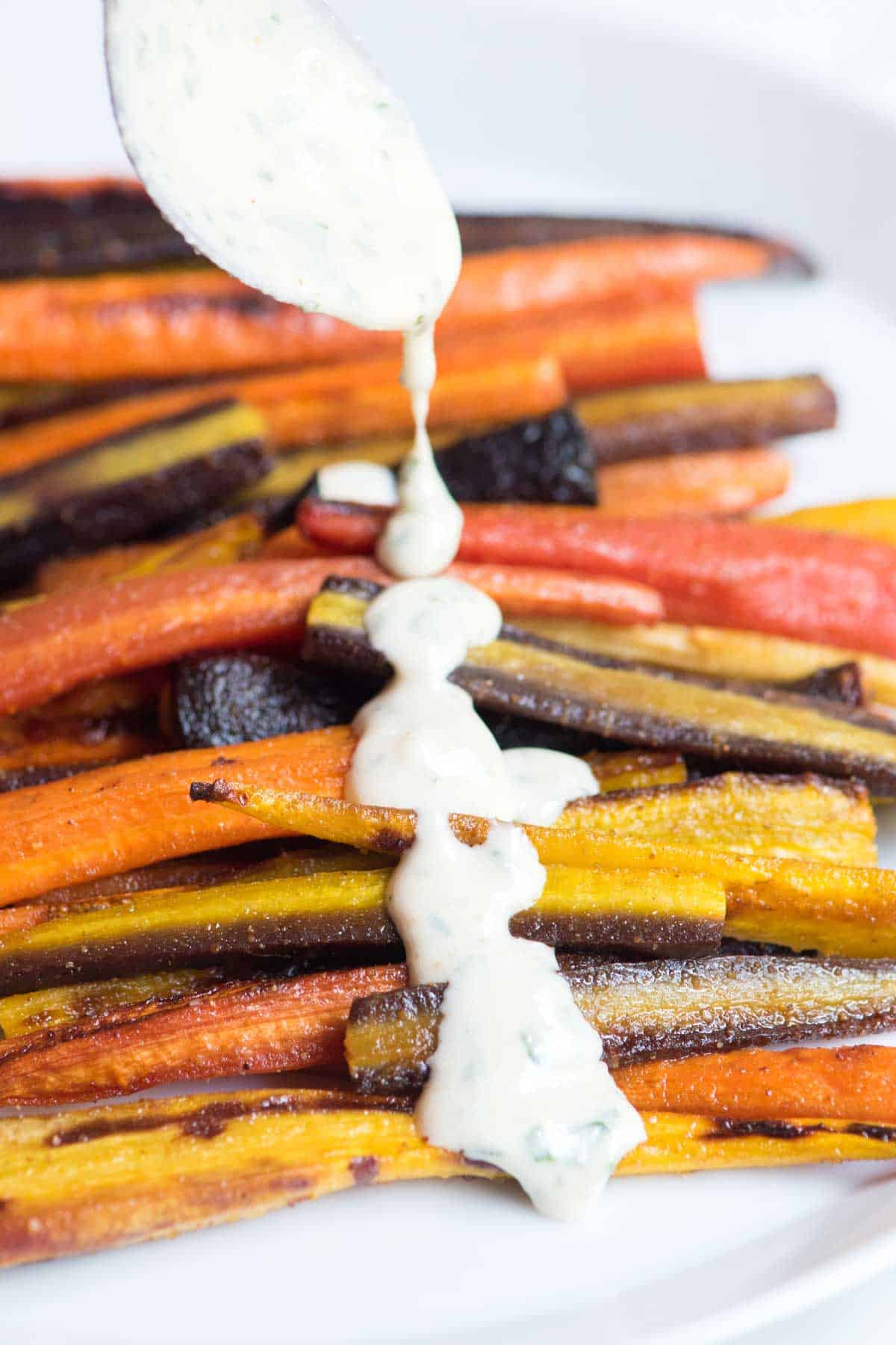 Honey Roasted Carrots with tahini sauce being drizzled on top