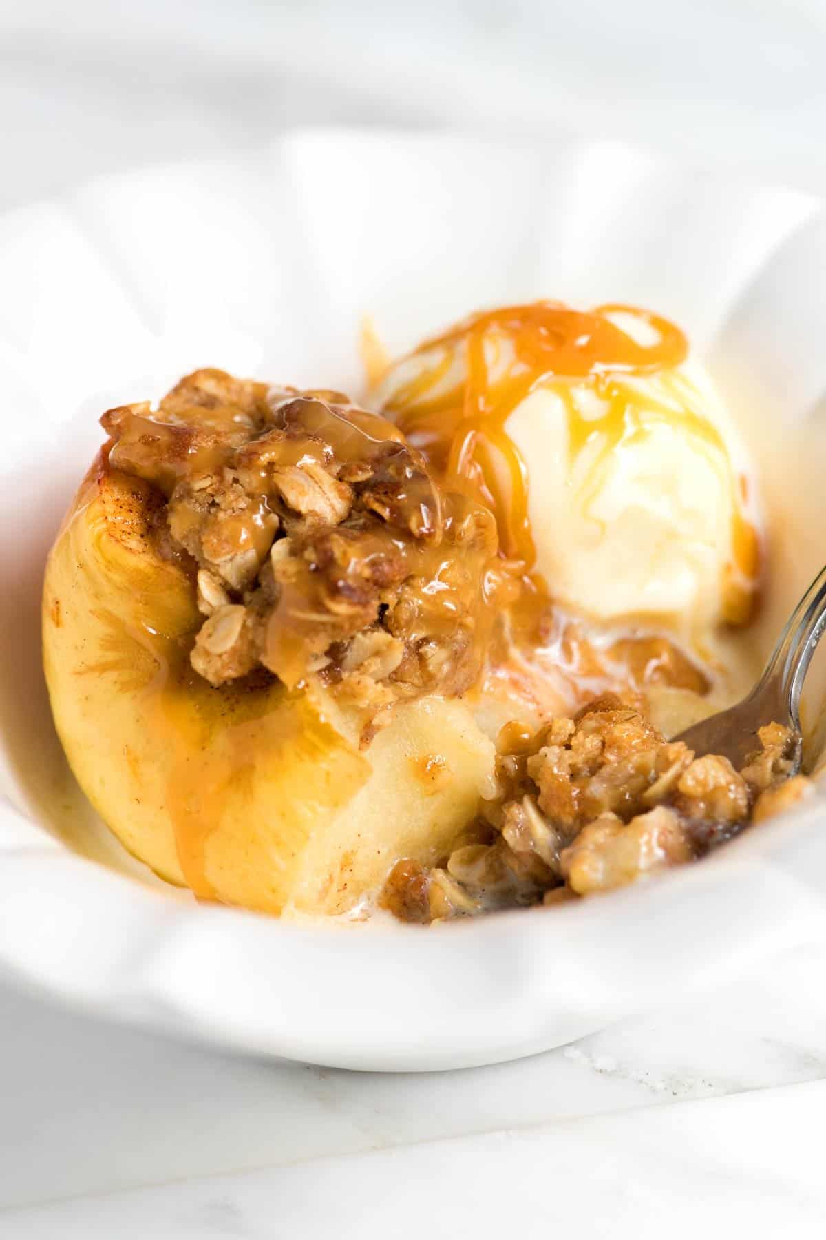 Serving cinnamon baked apples with ice cream and caramel sauce