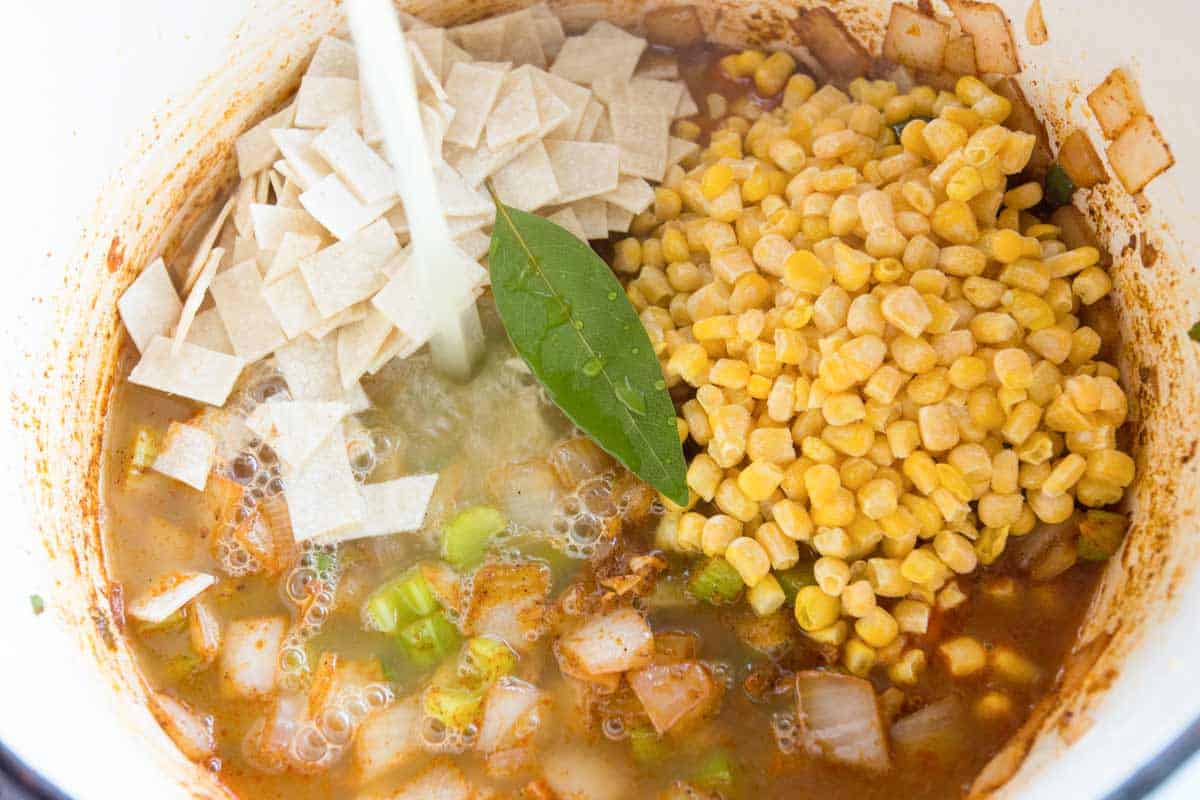 How to Make Chicken Tortilla Soup: Adding the chicken stock, tortillas, and corn.