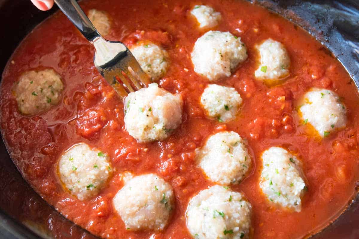 Adding the chicken meatballs to a slow cooker