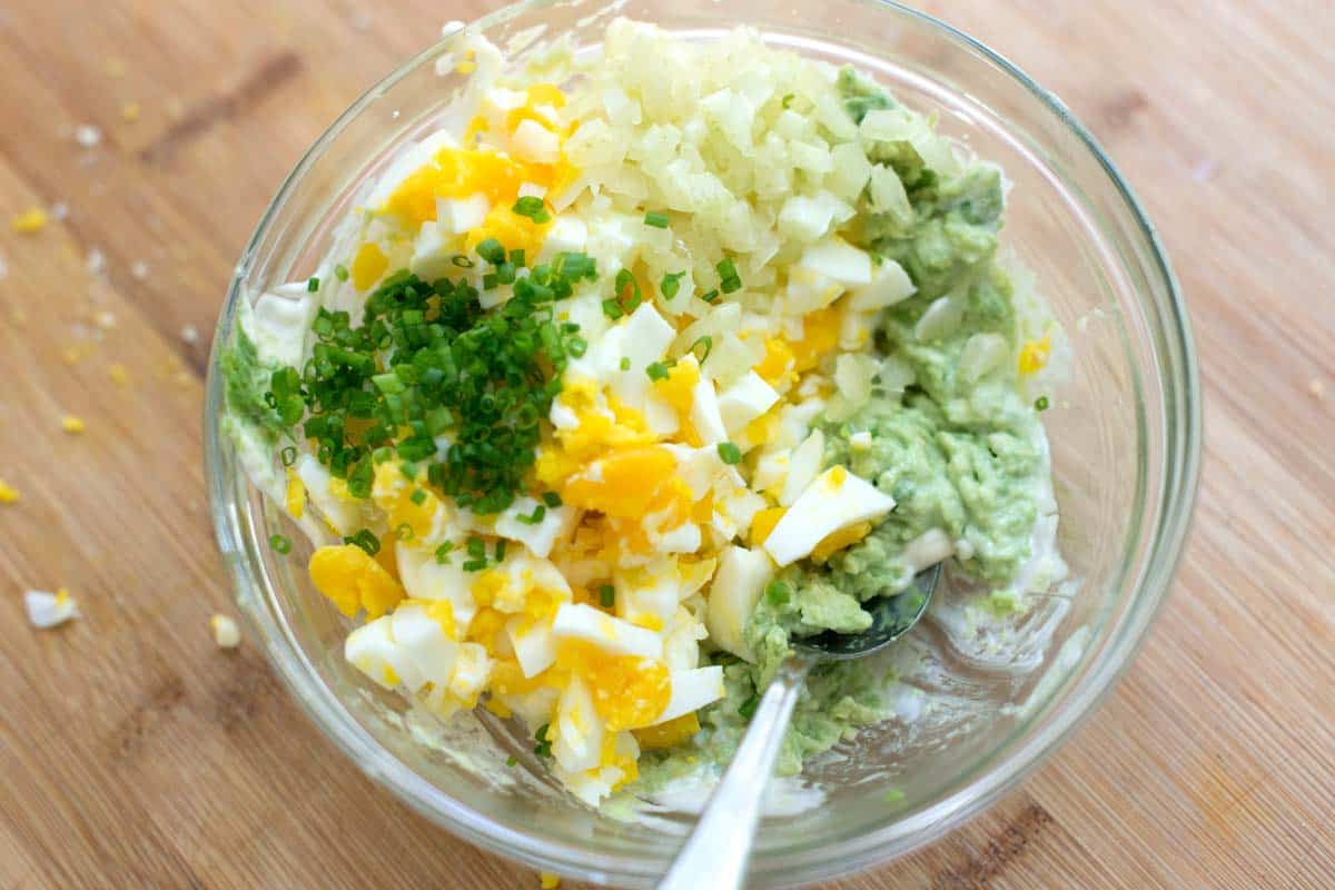 Bowl with hard-boiled eggs, avocado, celery, and fresh herbs for avocado egg salad