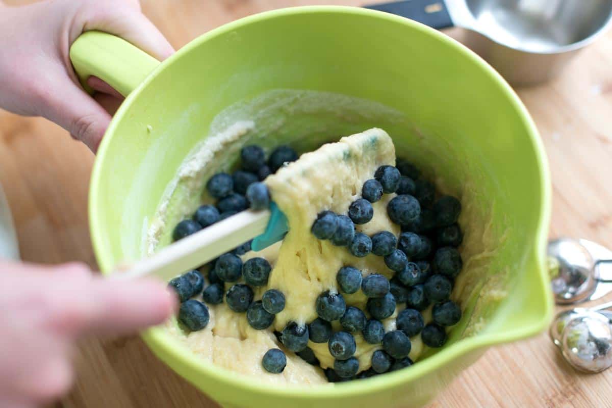 mixing blueberry muffin batter with blueberries