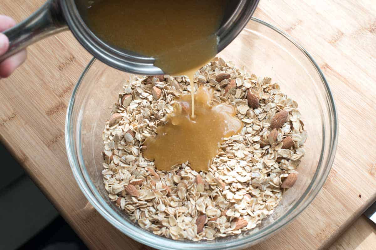 Pouring the sticky glue (made with butter, honey, and brown sugar) into oats for homemade granola bars