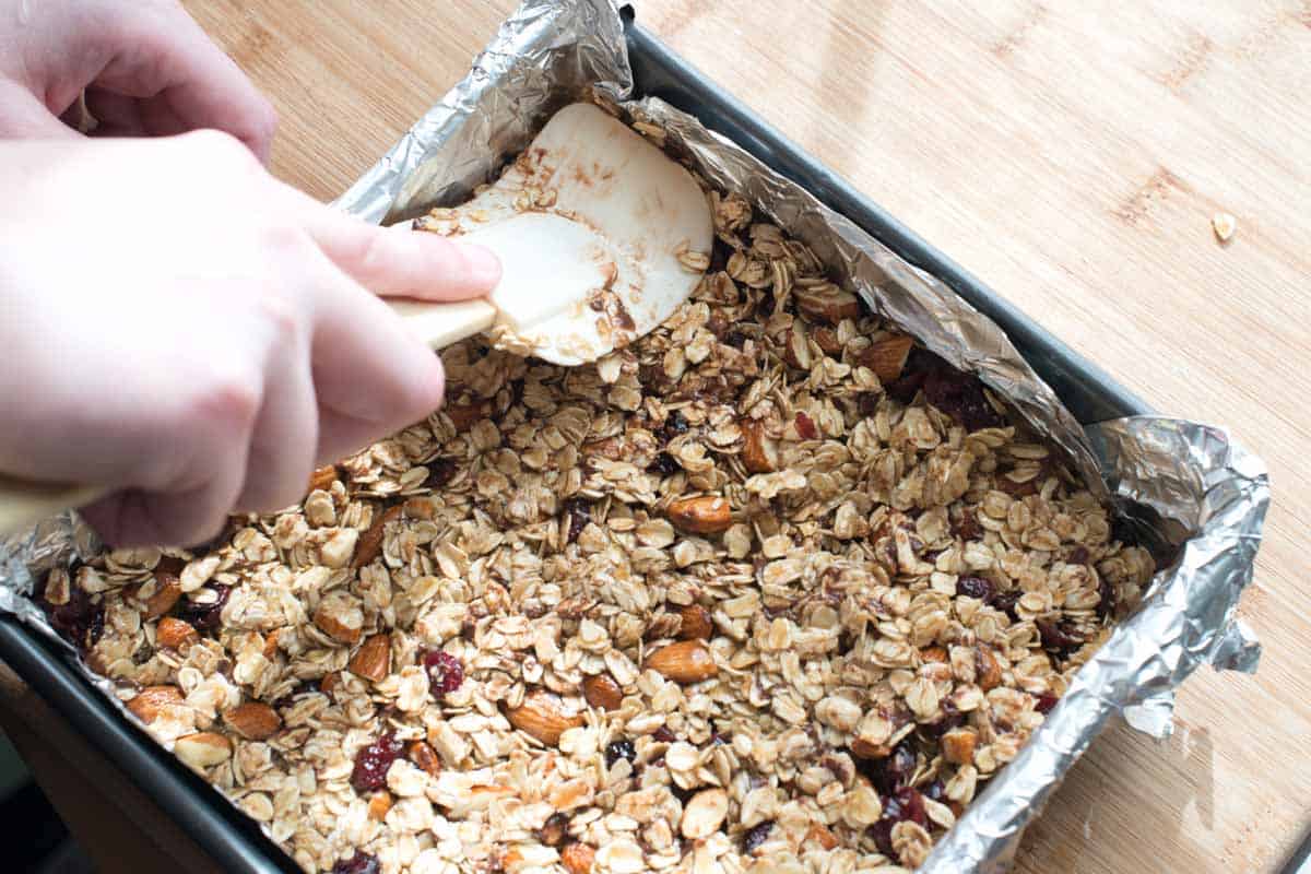 Pressing granola mixture into a pan before chilling and cutting into bars