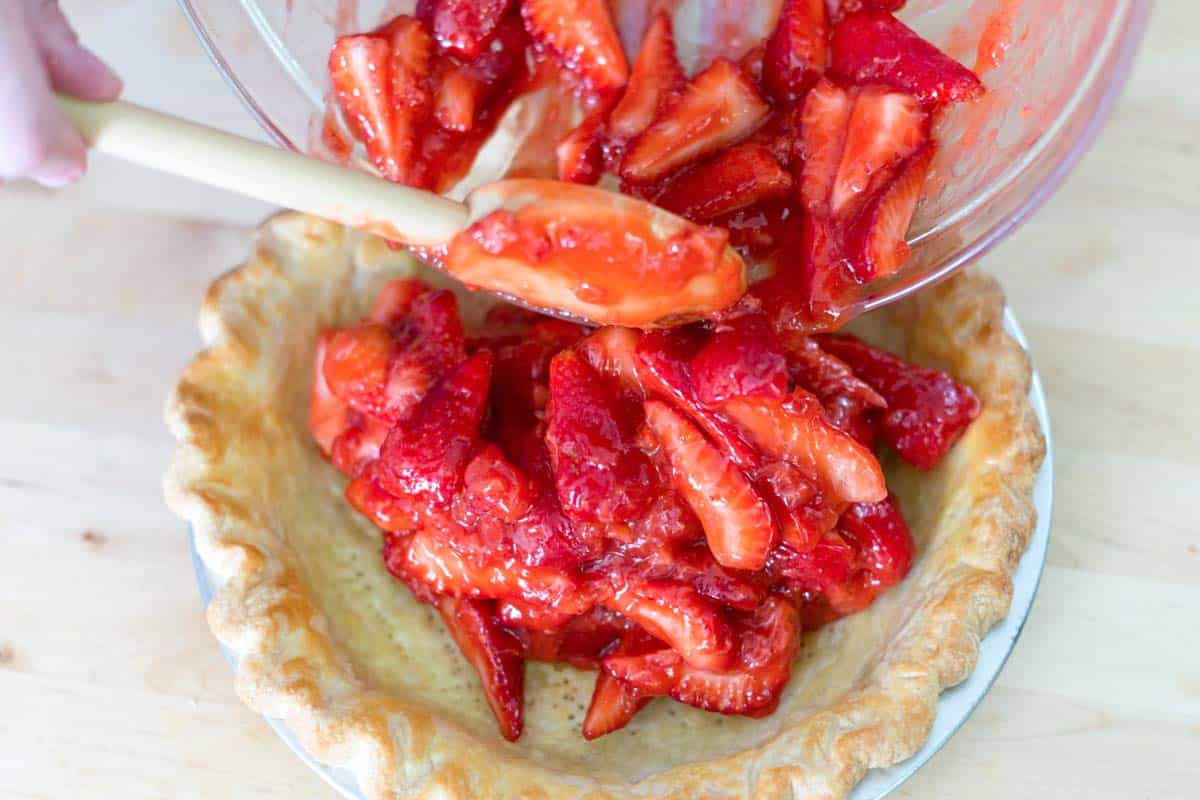 Adding the strawberry pie filling to the baked pie crust