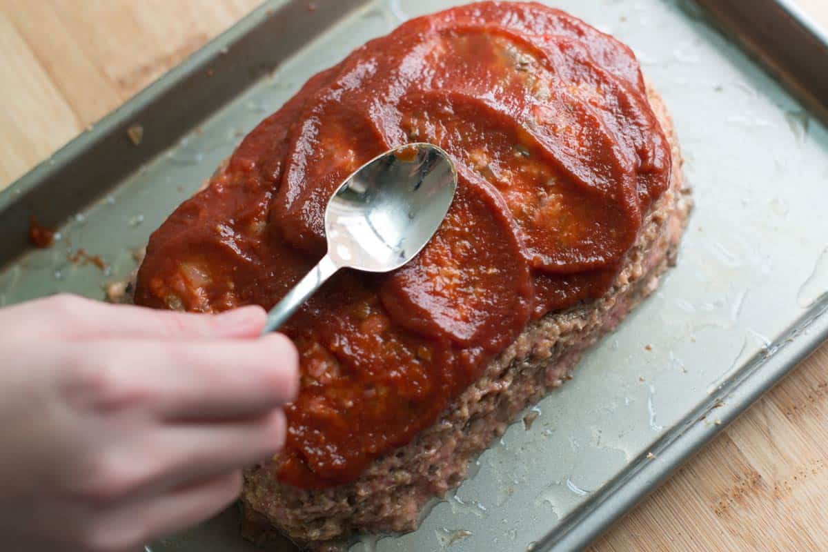 Adding ketchup to the top of turkey meatloaf for our glaze