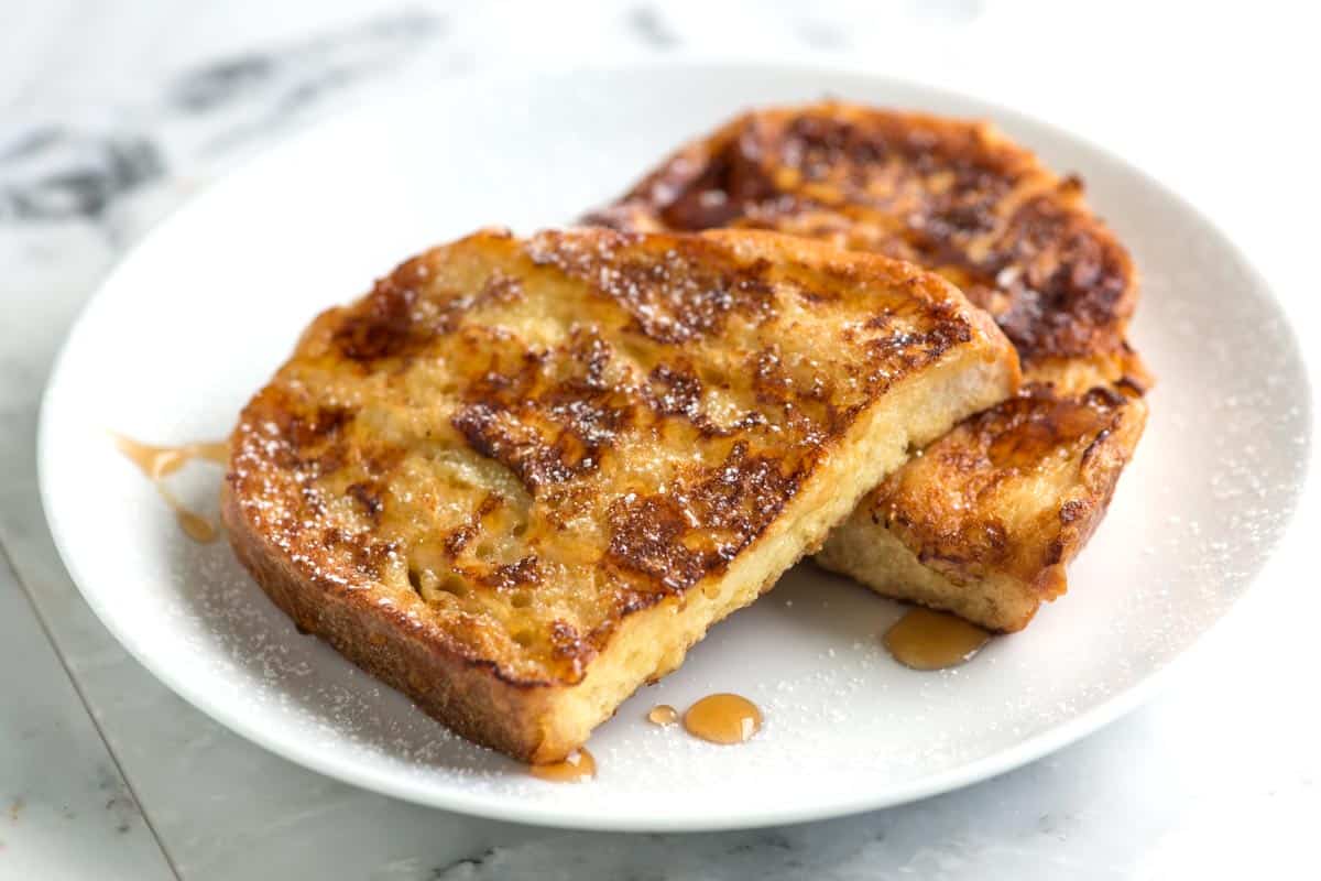 Thick slices of French toast dusted with powdered sugar on a plate