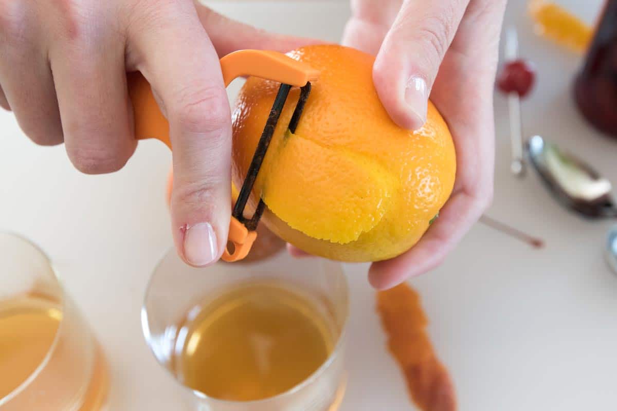 Old Fashioned Cocktail with Tips Peeling an orange for an old fashioned