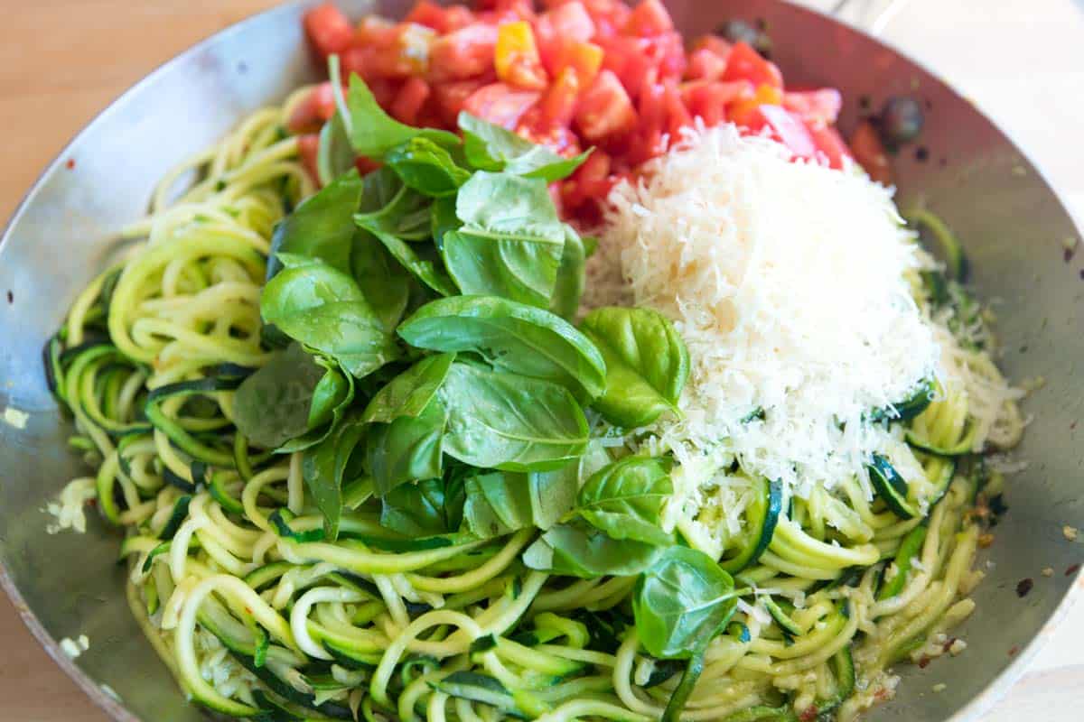 Cooking zucchini noodles (zoodles) with garlic, basil, and tomatoes