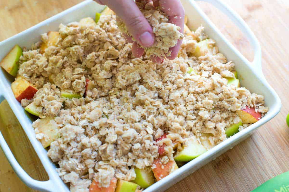 Adding the apple crisp oat topping to the apples