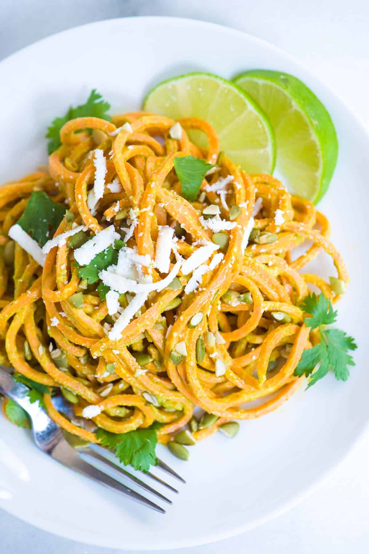 Sweet potato noodles with a creamy dairy-free avocado sauce and topped with pumpkin seeds.