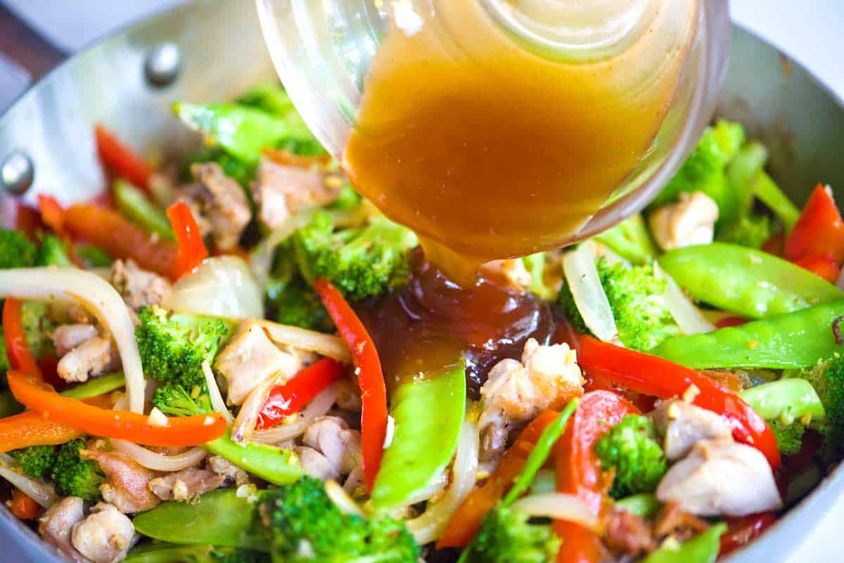 Adding the homemade stir fry sauce to the skillet for the ginger chicken stir fry