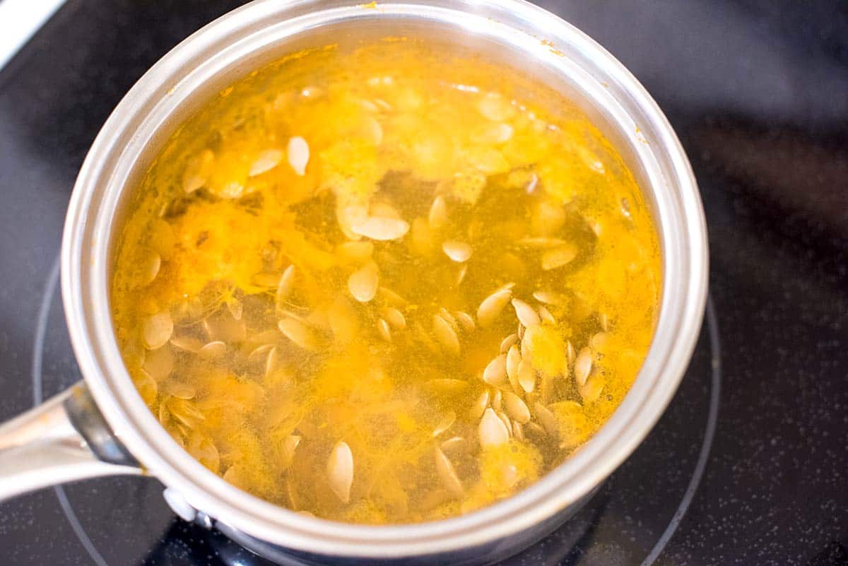 Simmering pumpkin seeds before roasting them.