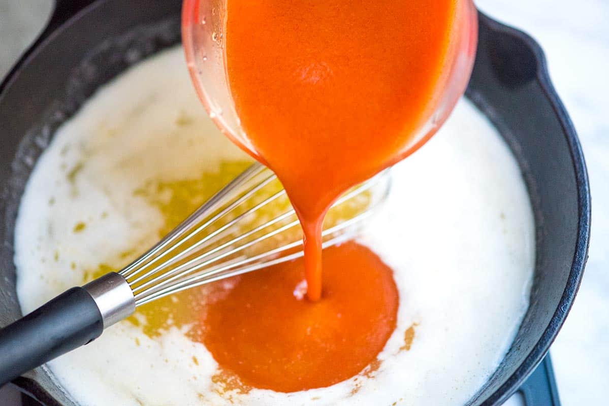 How to make buffalo wing sauce: Mixing melted butter with hot sauce and garlic powder.