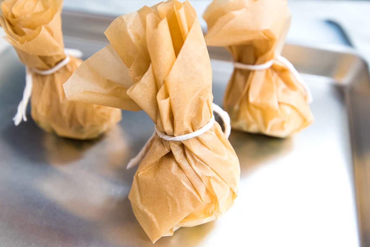 Garlic inside parchment paper packets before roasting.