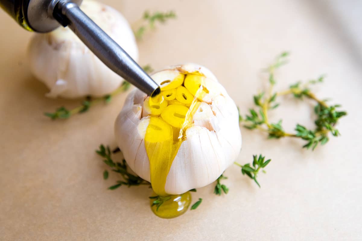 How to Roast Garlic in the Oven Garlic with olive oil, salt, pepper and fresh thyme. Preparing for roasted garlic.