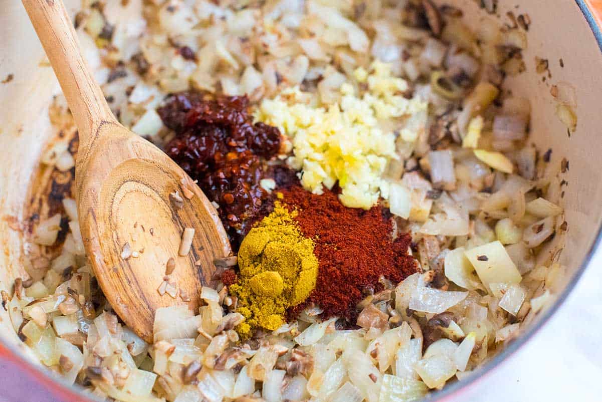 How to Make Bean Chili: Chili spices, chipotles, onions, and garlic in a pot.