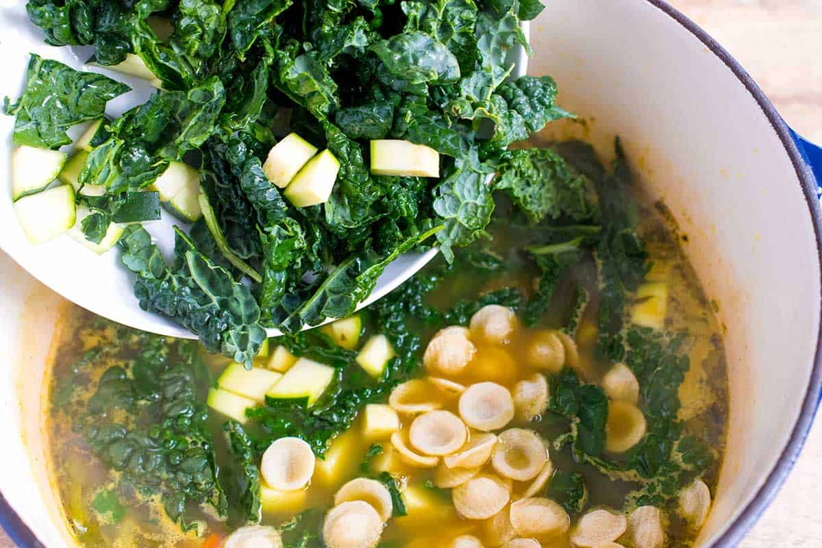 Adding the kale and zucchini to the chicken soup