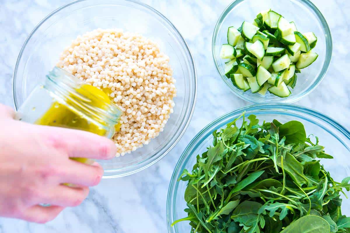 Adding lemon vinaigrette to couscous for the arugula and couscous salad