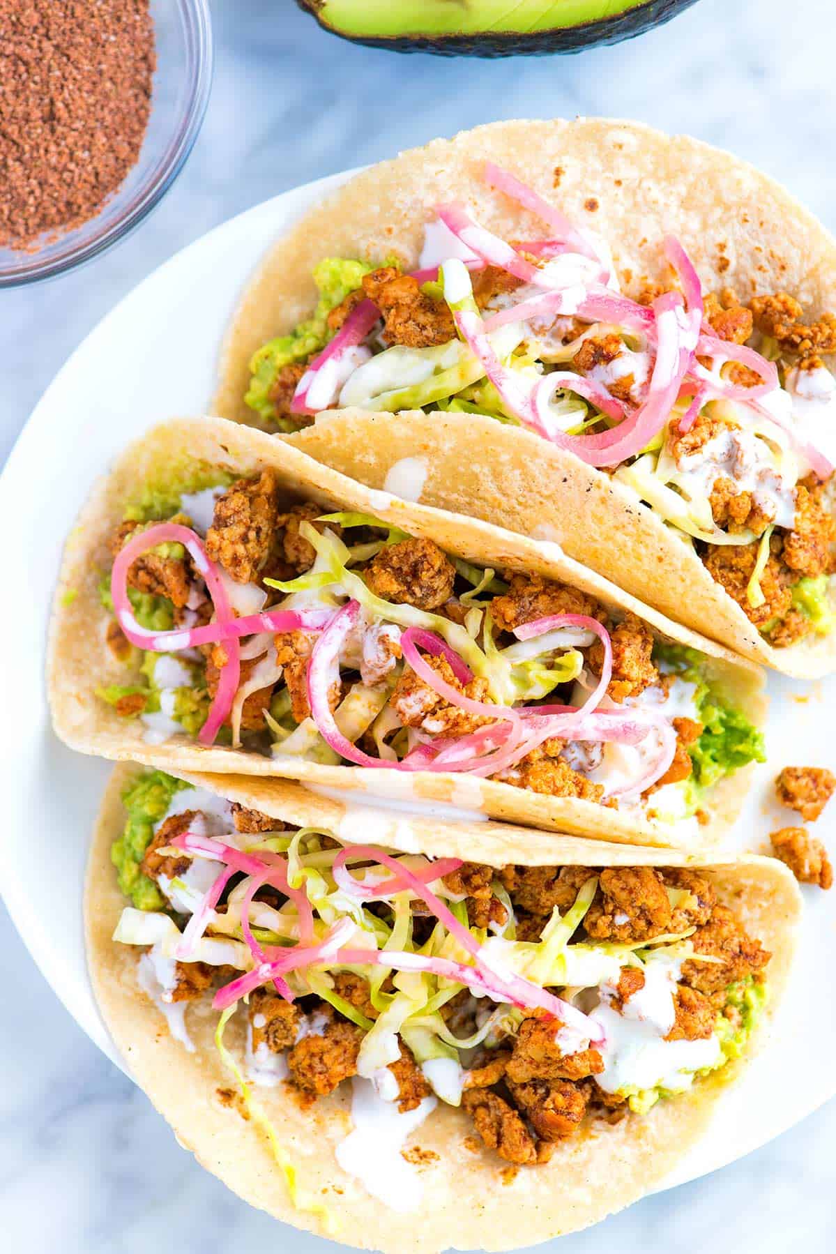 Tacos made with ground pork, avocado, and pickled onions